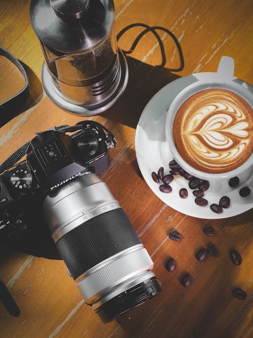 A camera and coffee on a table with a cup of coffee