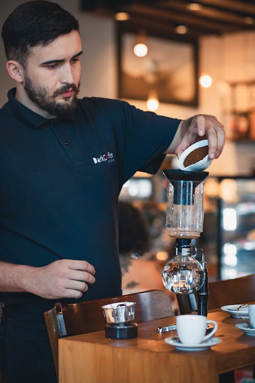 A man in a black shirt is making coffee