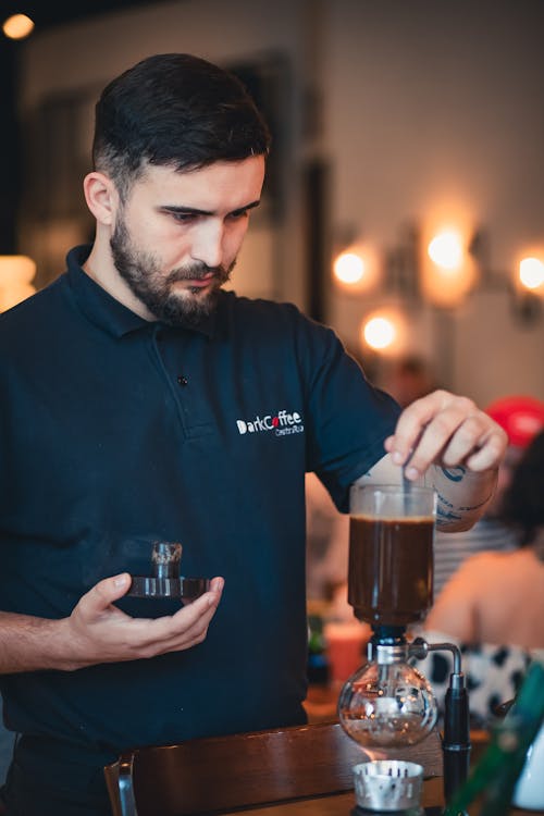 A man in a black shirt pouring coffee into a cup