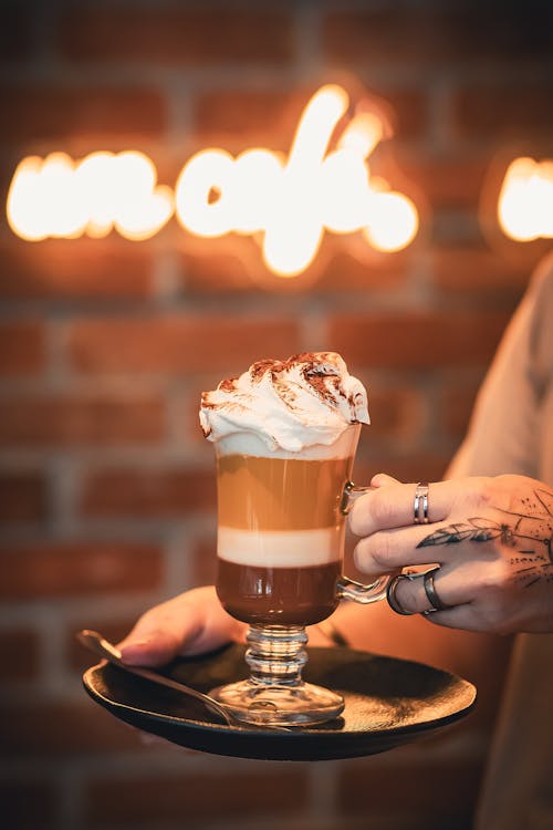 A person holding a cup of coffee with whipped cream