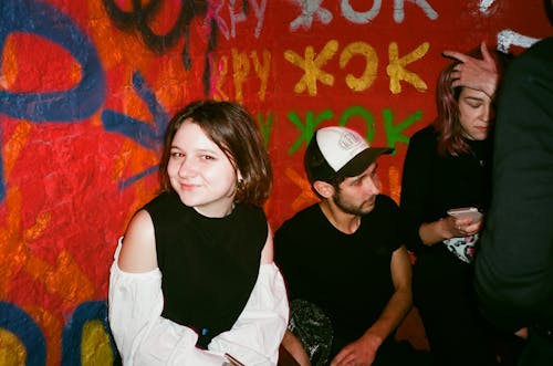 Women and Man Sitting Beside Wall