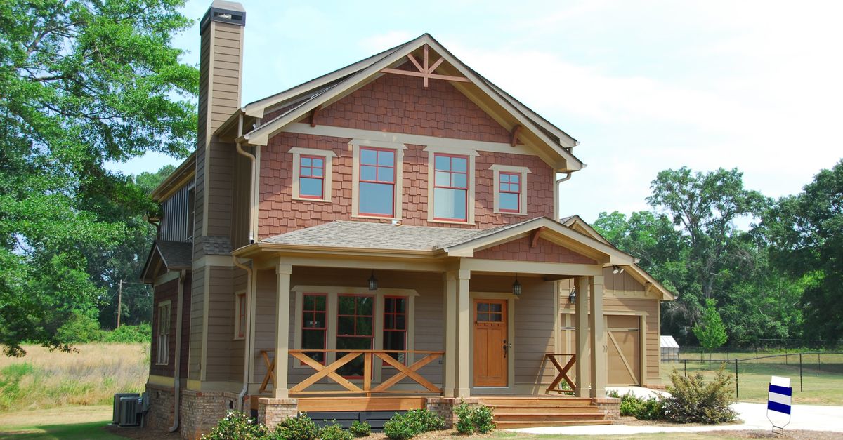 Charming single-family home with a porch, lawn, and trees, ideal for real estate use.