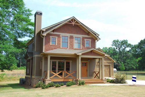 Free Charming single-family home with a porch, lawn, and trees, ideal for real estate use. Stock Photo