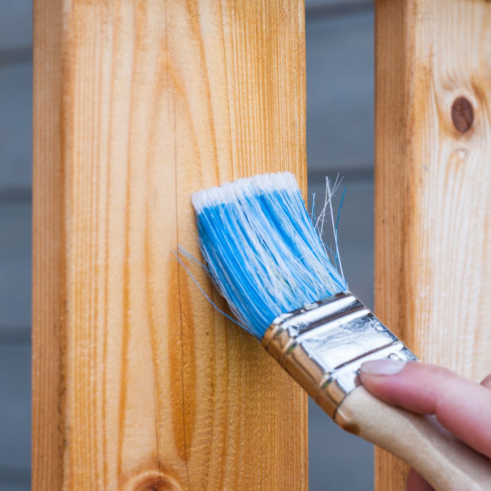Hand painting garden timber with a brush and wood paint