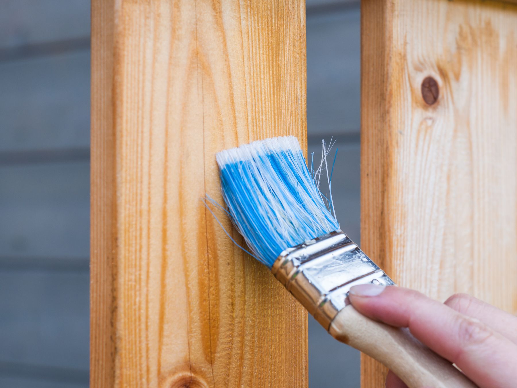 Hand painting garden timber with a brush and wood paint