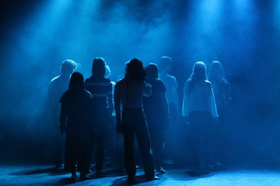 Performers silhouetted in haze and blue light