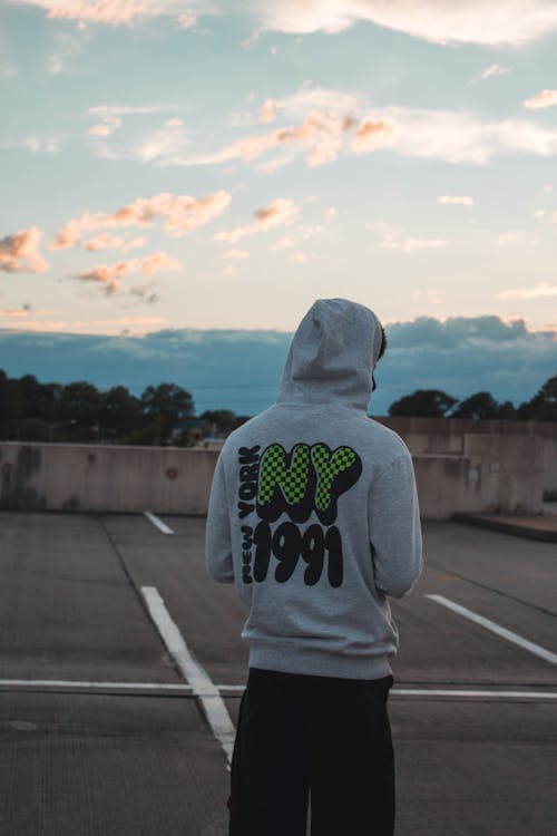 Free Rear view of Man Wearing Gray Pullover Hoodie and Black Pants at Parking Lot Stock Photo