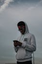 Man Wearing a Hoodie Holding Smartphone