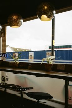 Warm café interior with modern lamps, counter seating, and a large window view.