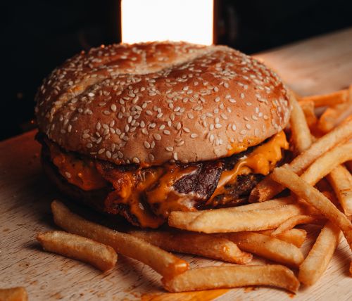 Free Appetizing cheeseburger with crispy fries captured in a cozy indoor setting. Stock Photo