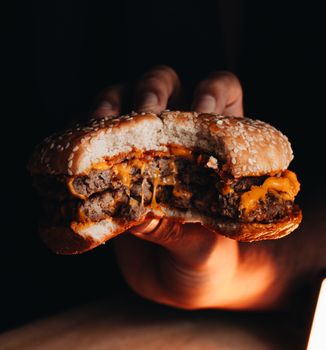 Mouth-watering cheeseburger in a dimly lit setting, perfect for food lovers.