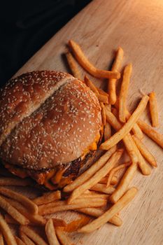 Mouthwatering cheeseburger with crispy fries served on a wooden board, perfect for lunch.