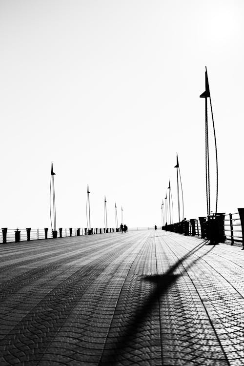 Black and white photo of a pier with a person walking