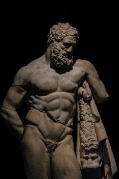 Marble statue of Heracles from ancient Greece in a museum setting.