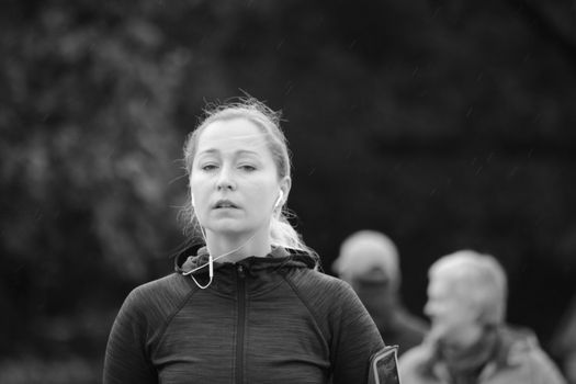 Black and white portrait of a woman exercising outdoors with earphones.