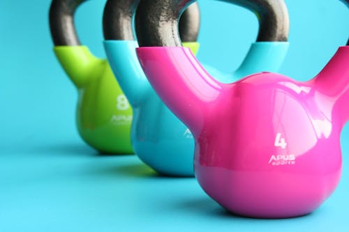 Green, Blue, and Pink Kettle Bells on Blue Surface