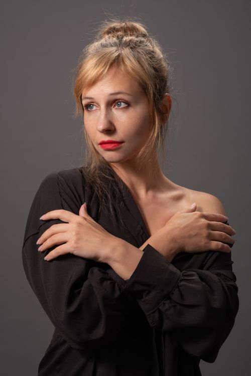 Free Studio portrait of a blonde woman with crossed arms wearing a black top, against a gray background. Stock Photo