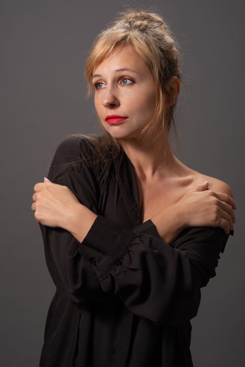 Free Studio portrait of a woman with blonde hair and red lipstick, wearing a black top against a gray background. Stock Photo