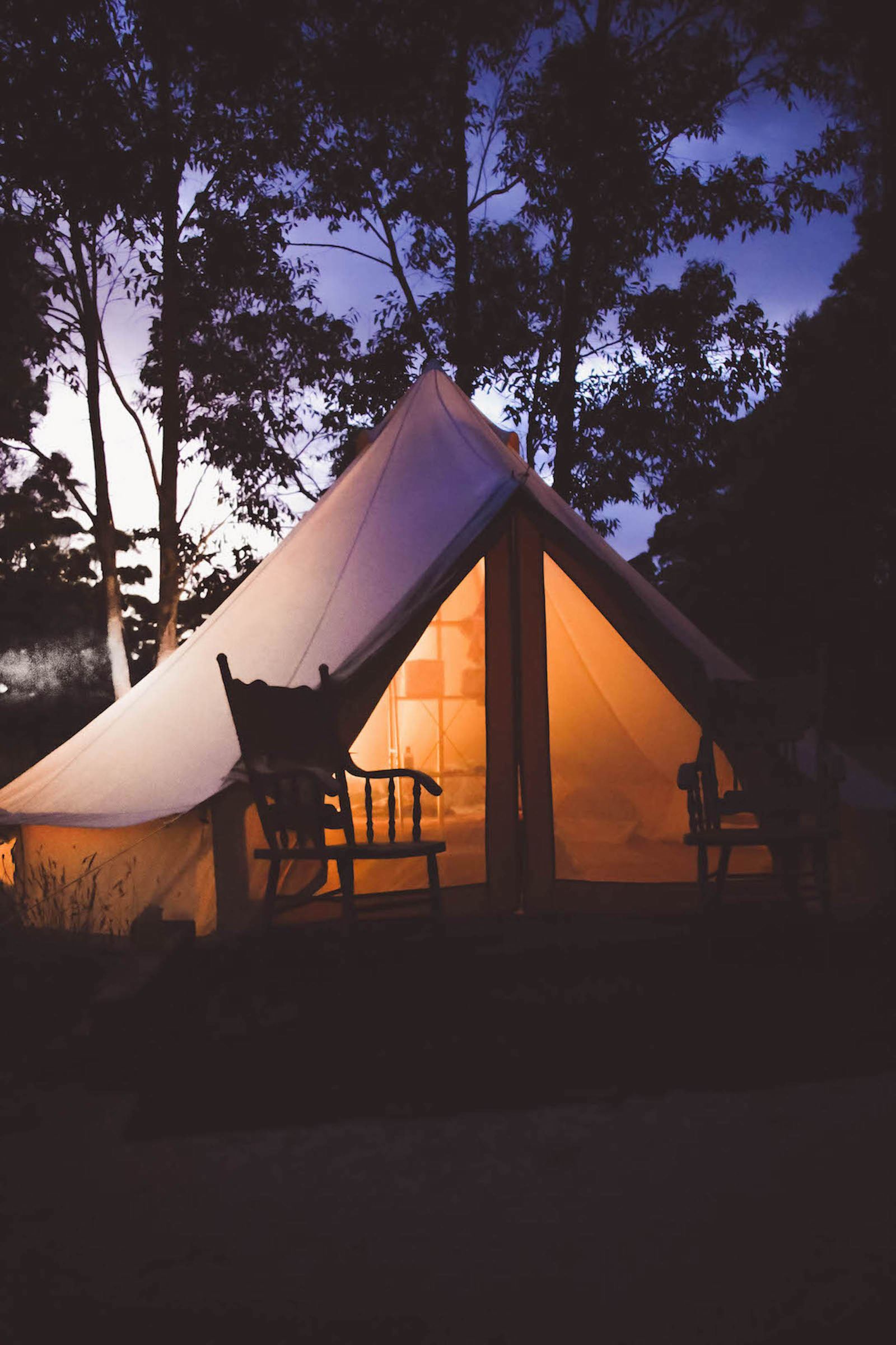 Warmly illuminated camping tent in the Western Australian bush at dusk