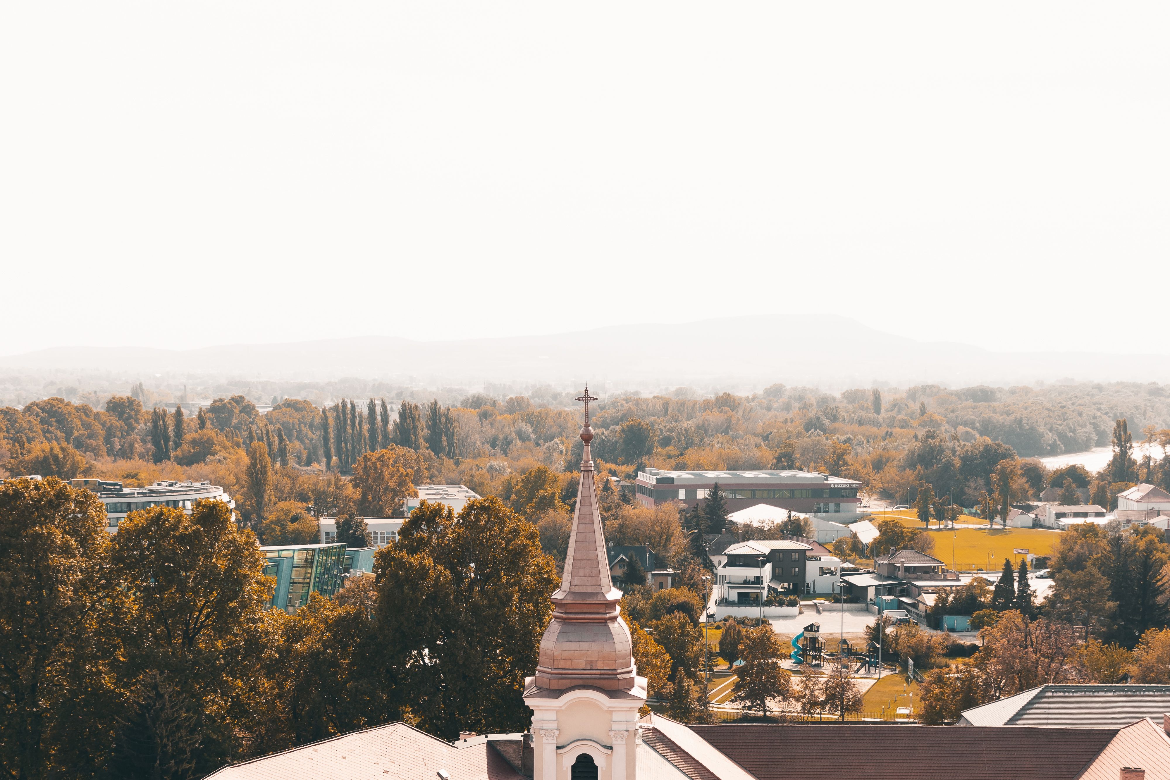 Captivating autumn view of a church steeple amidst colorful foliage in Esztergom, Hungary.