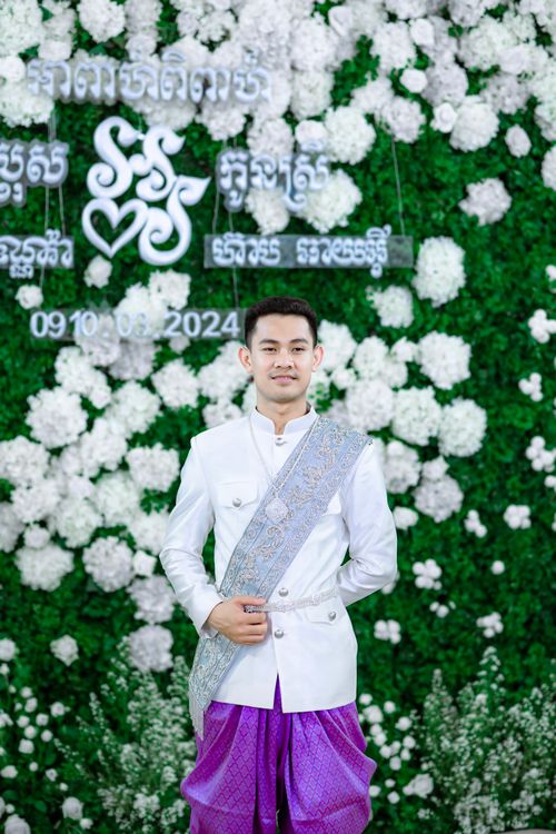 Free Young man in traditional Cambodian wedding attire with floral backdrop. Stock Photo