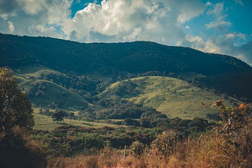 Free Beautiful mountain scenery with lush greenery under a cloudy blue sky, ideal for nature lovers. Stock Photo