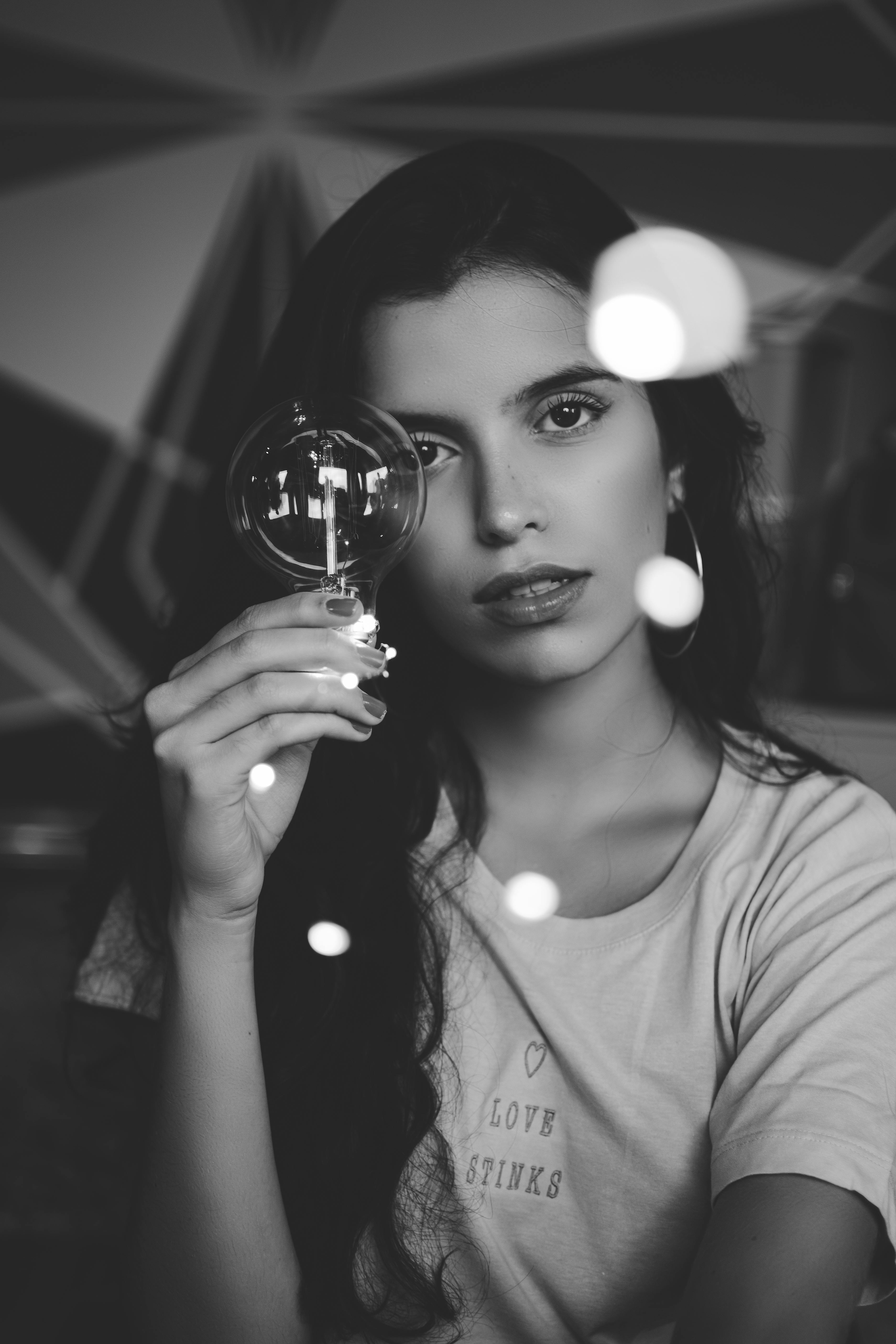 一幅时尚的黑白肖像中，灯泡映照着一位女性，展现出其现代与艺术的天赋