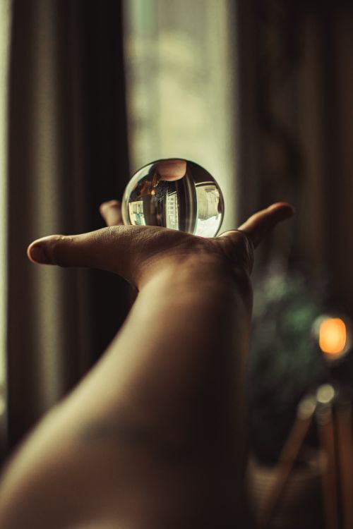 Free A close-up shot of a hand holding a reflective glass ball, creating an intriguing visual effect indoors. Stock Photo