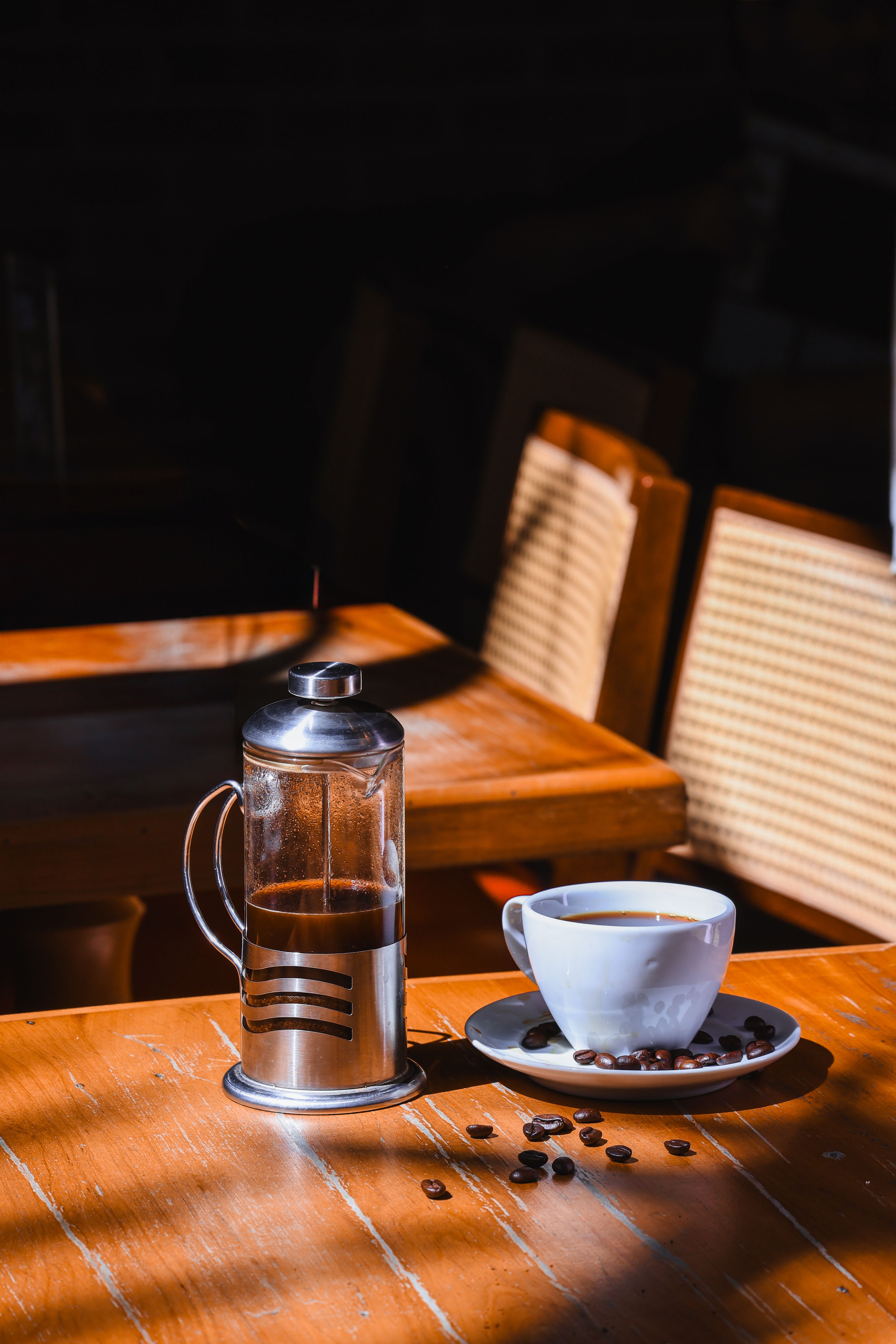 A serene coffee scene with French press and cup on a sunlit table.