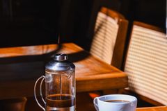 A serene coffee scene with French press and cup on a sunlit table.