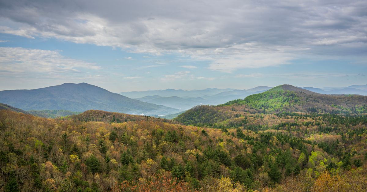 A breathtaking view of rolling hills and forests under a cloudy sky, capturing the essence of nature's beauty.