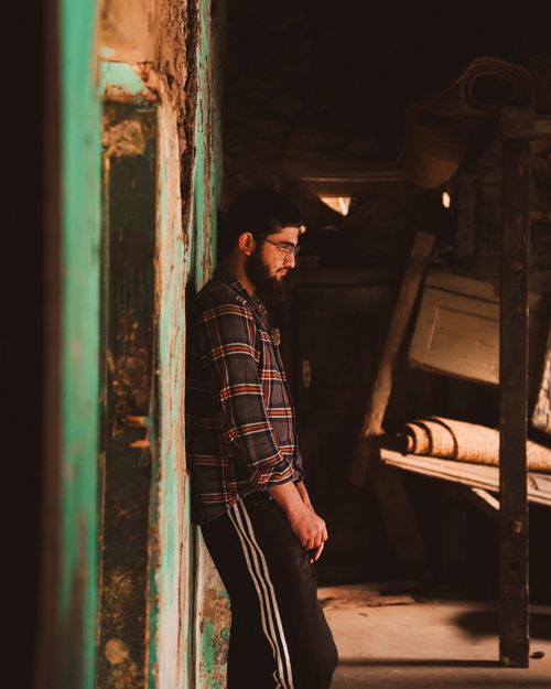 Free A young man leans on a wall in an atmospheric, rustic interior. Stock Photo