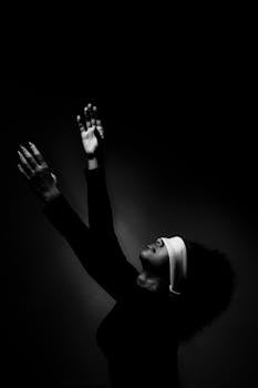 一张黑白照片中，一名女子被蒙住眼睛、举起双臂，画面充满戏剧性