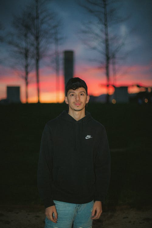 A young man standing in front of a sunset