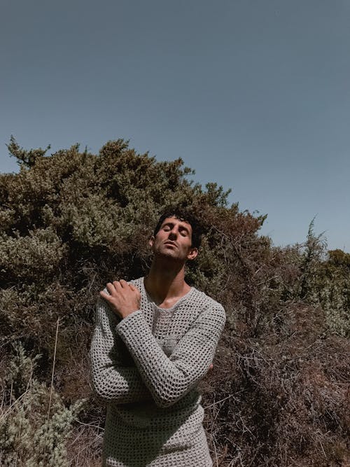A man in a sweater standing in the woods
