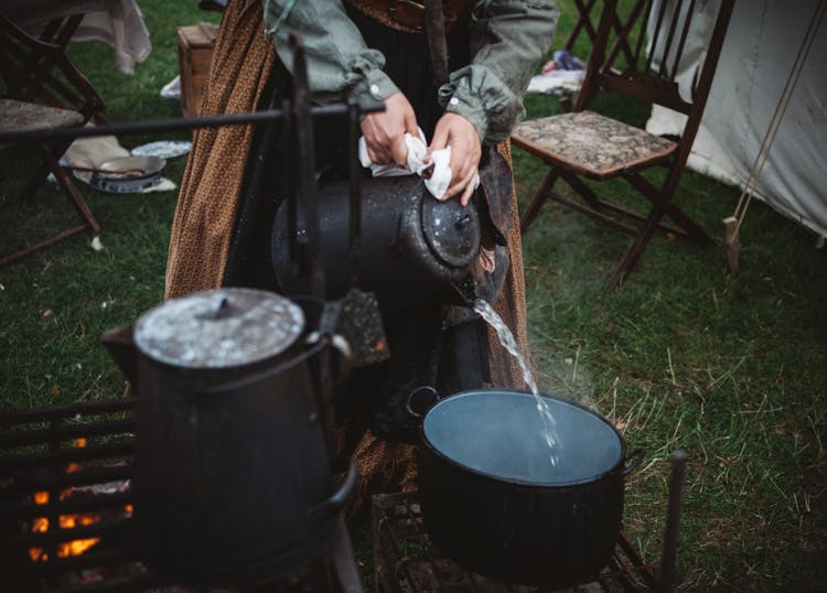 Person Pouring Water On Cooking Pot