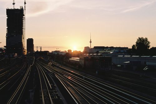 Free Beautiful sunset over Berlin's railway, featuring the iconic TV Tower and city silhouette in the distance. Stock Photo