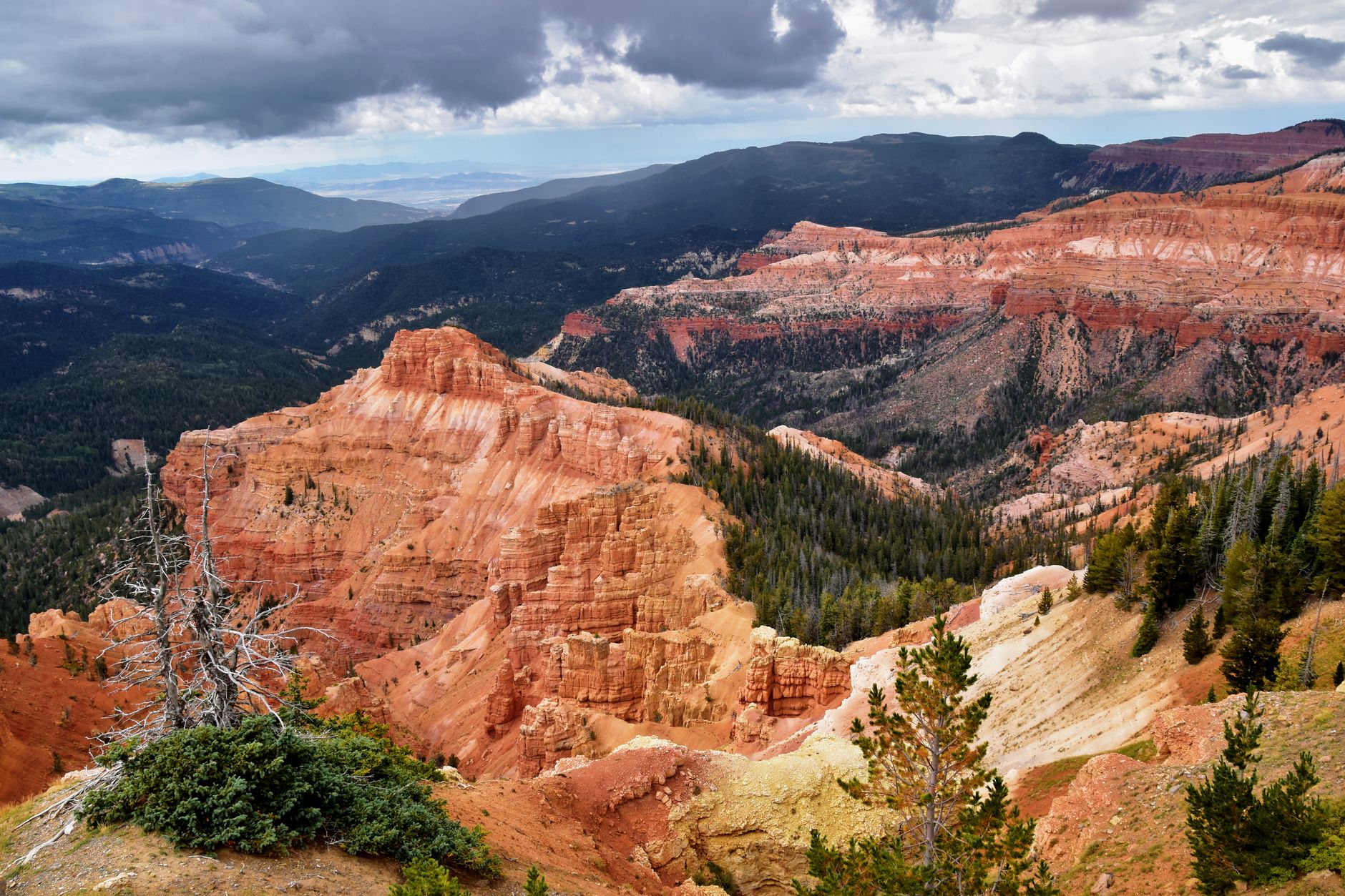 Breathtaking aerial shot of Cedar Breaks National Monument showcasing vibrant red rock formations and lush green forests.