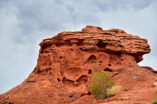 Free Eroded red rock formation under cloudy sky in St. George, UT's rugged landscape. Stock Photo