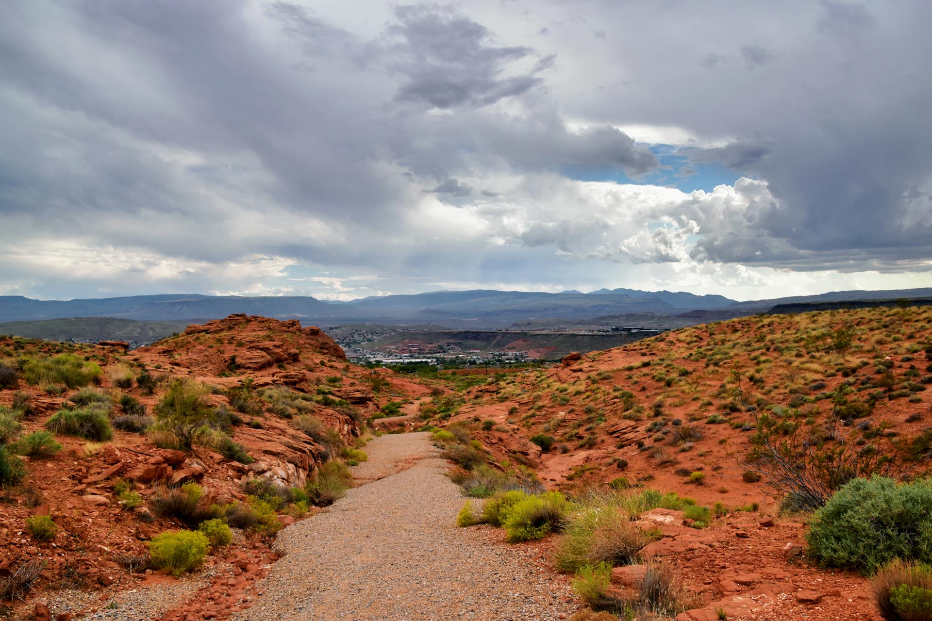 Peaceful desert path with stunning views of St. George, Utah under a dramatic sky.