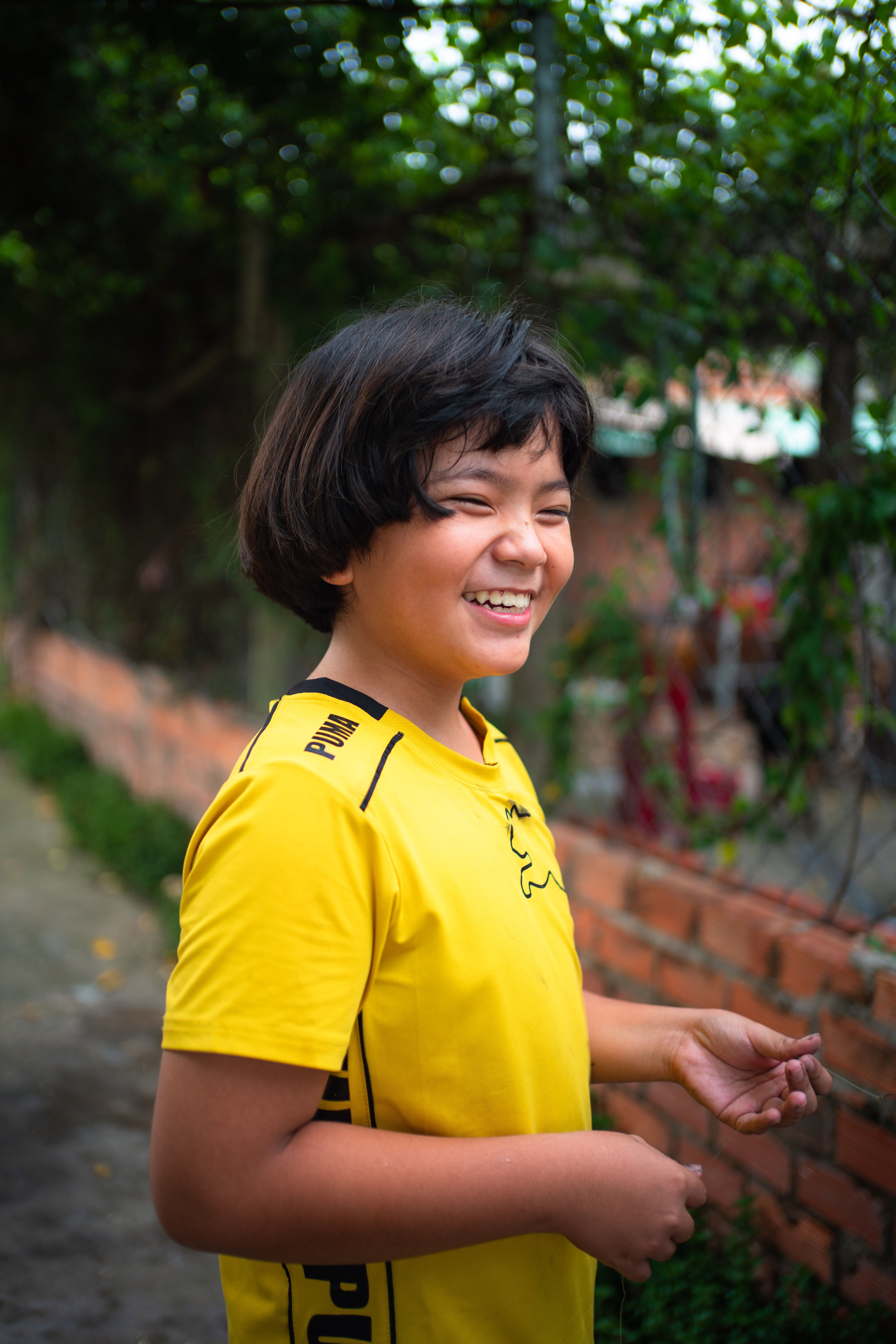 A Happy Young Boy in a Yellow T-shirt Standing Outside · Free Stock Photo