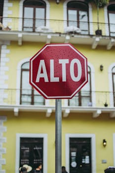 A vibrant stop sign with the word 'Alto' in Panama City against a yellow colonial building backdrop.