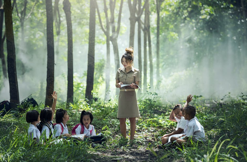 Woman in Gray Long Sleeve Dress Standing Between Childrens Near Woods and Grass