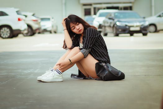 一位年轻女子坐在城市停车场的人行道上，造型时尚，表情从容