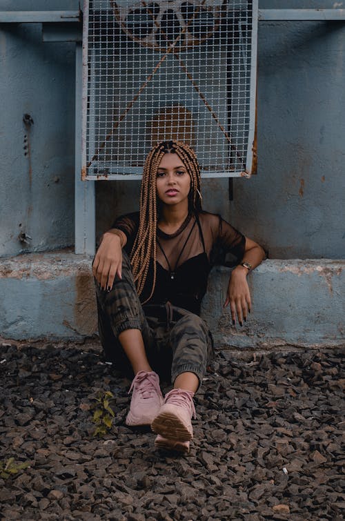 Woman Sitting on Ground Leaning on Concrete Wall