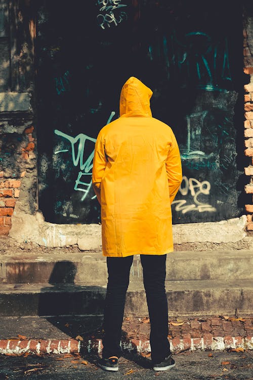 Person Standing Near Brown Structure in Yellow raincoat · Free Stock Photo