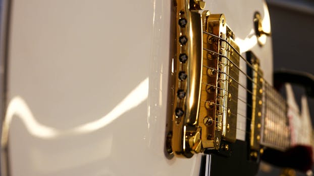 Detailed view of a white electric guitar with a gold bridge, emphasizing luxury and style.