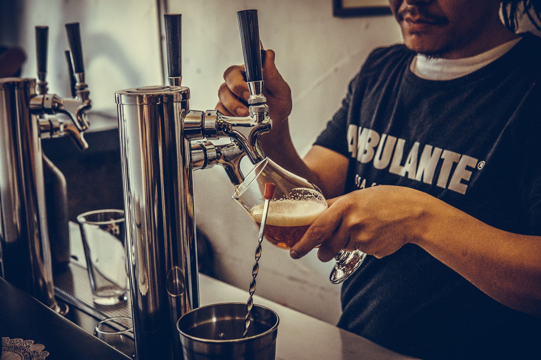 Man pouring craft beer from tap at a bar, capturing casual pub atmosphere.