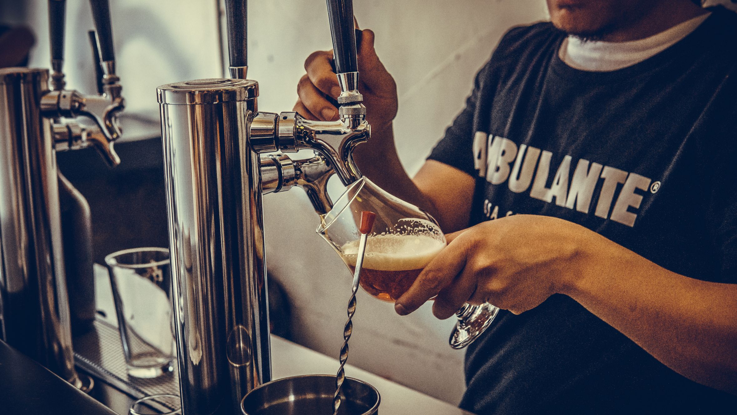 Man pouring craft beer from tap at a bar, capturing casual pub atmosphere.