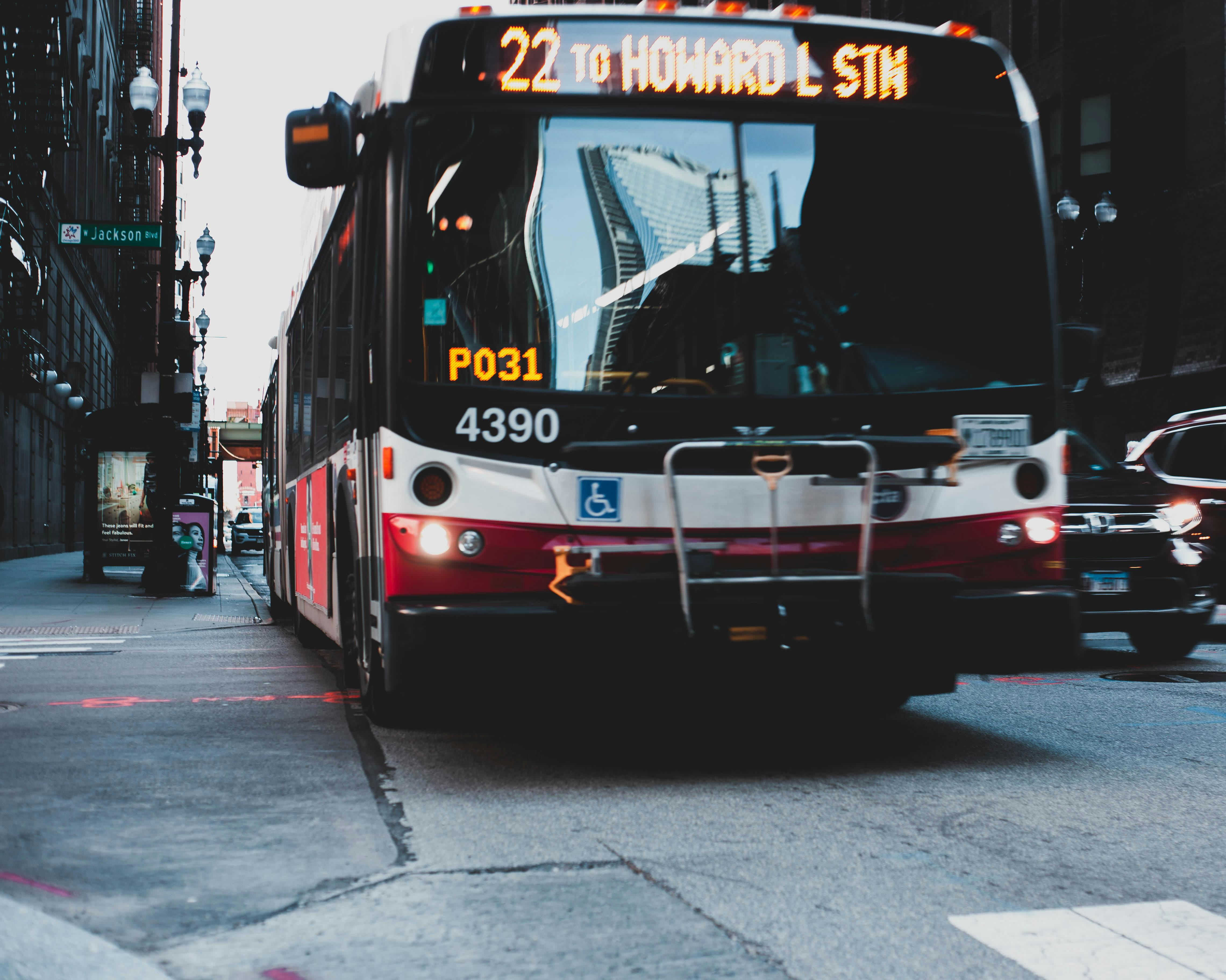 Red and white bus on the road. | Photo: Pexels